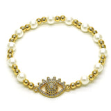 Elegant bracelet featuring alternating faux pearls and gold beads with a central gold evil eye charm embellished with clear rhinestones, designed for both style and protection.