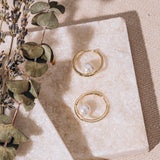 gold hoop earring on crystal stone background with large pearl
