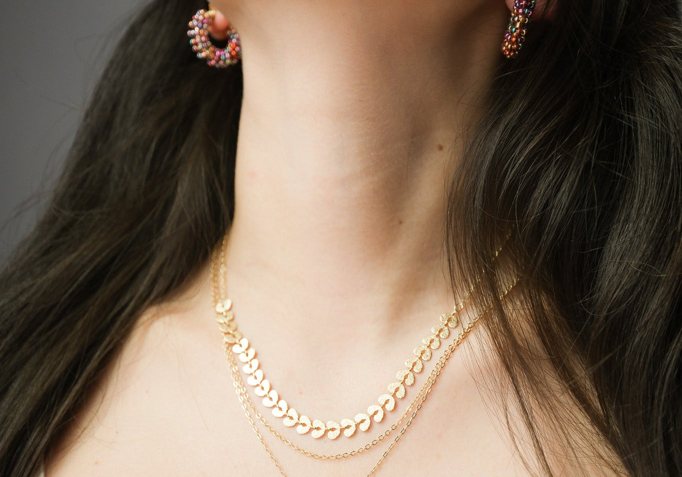Woman wearing layered gold necklaces in different lengths